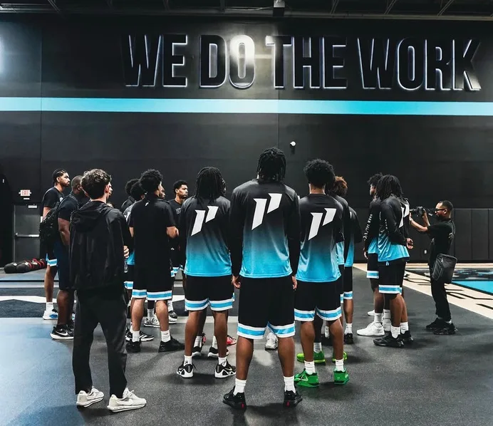 College players in 1st Phorm uniforms gathered on the court during a camp